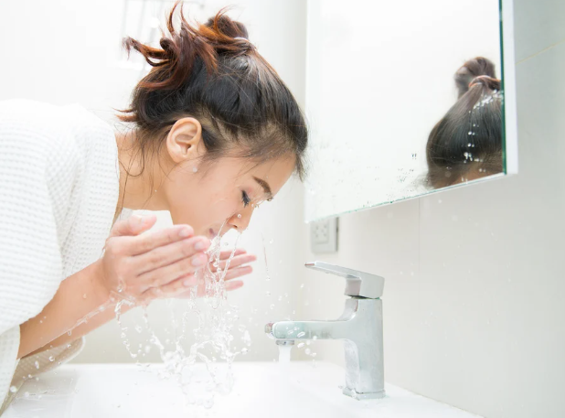 洗面台で顔を洗っている女性